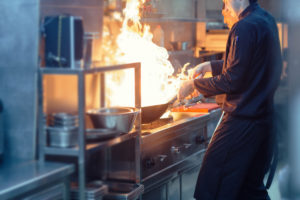 Chefs cooking over an open flame in a restaurant kitchen