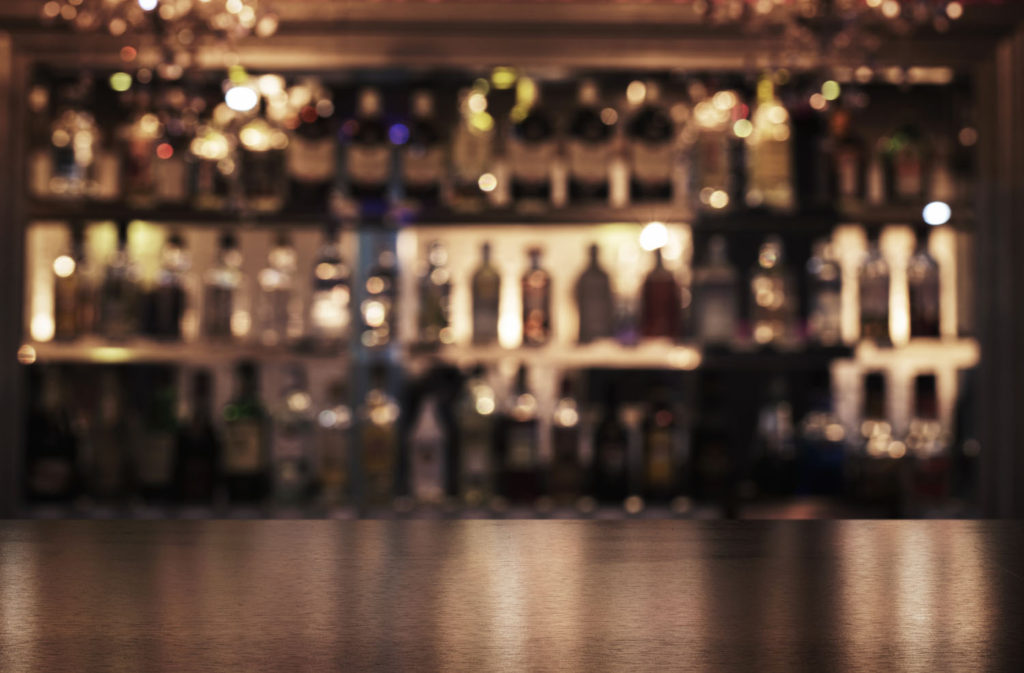 Close up of a bar counter with defocused bottles in the background