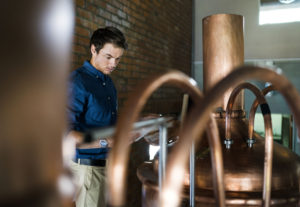 Male worker examining metallic vat in brewery